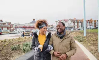 A couple walking arm-in-arm catching up over a coffee