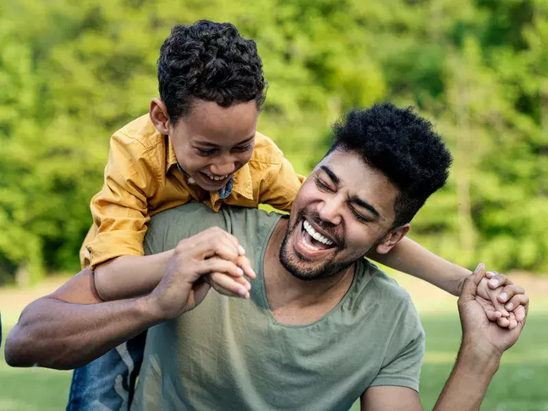 A boy is having fun with his father in the park